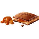 A square of Milka Caramel Milk Chocolate out of the package with caramel filling visible.